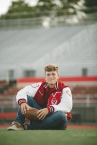 High school senior boy sitting on football field at Moon Area High School near Pittsburgh