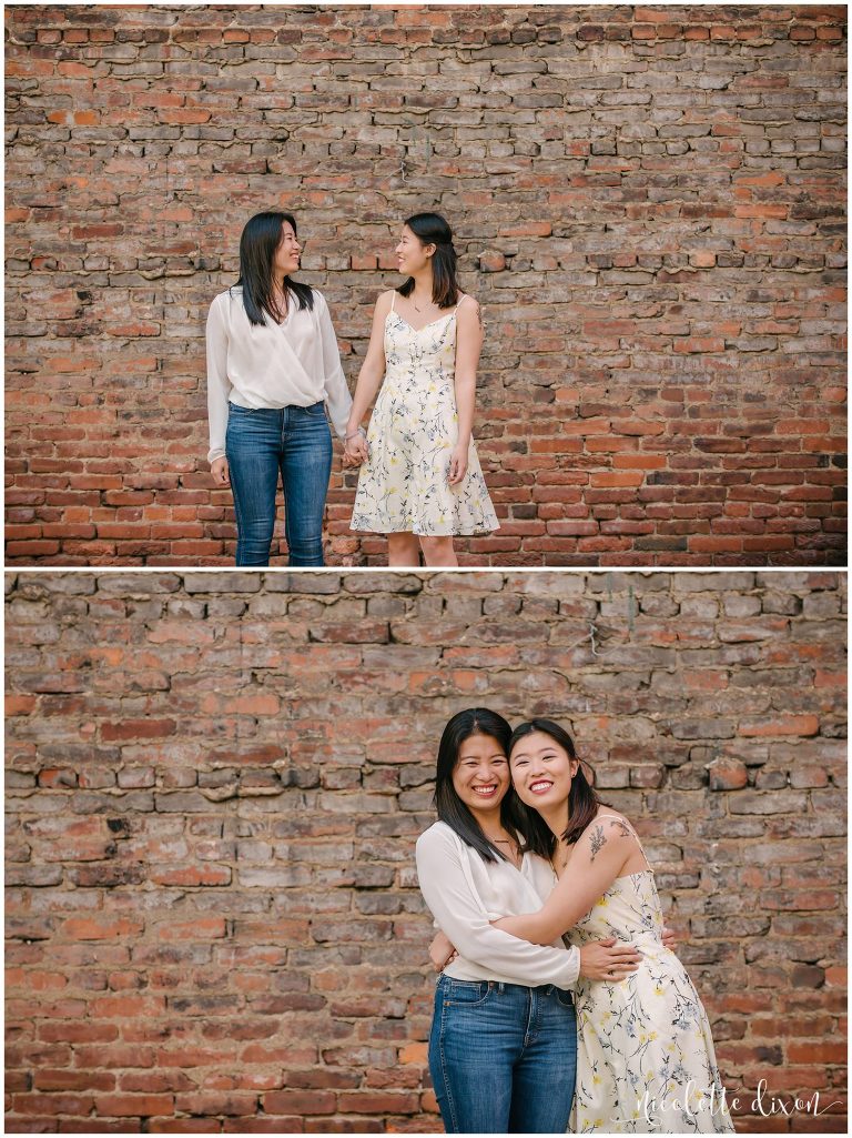 Sisters hugging each other in front of brick wall in downtown Pittsburgh