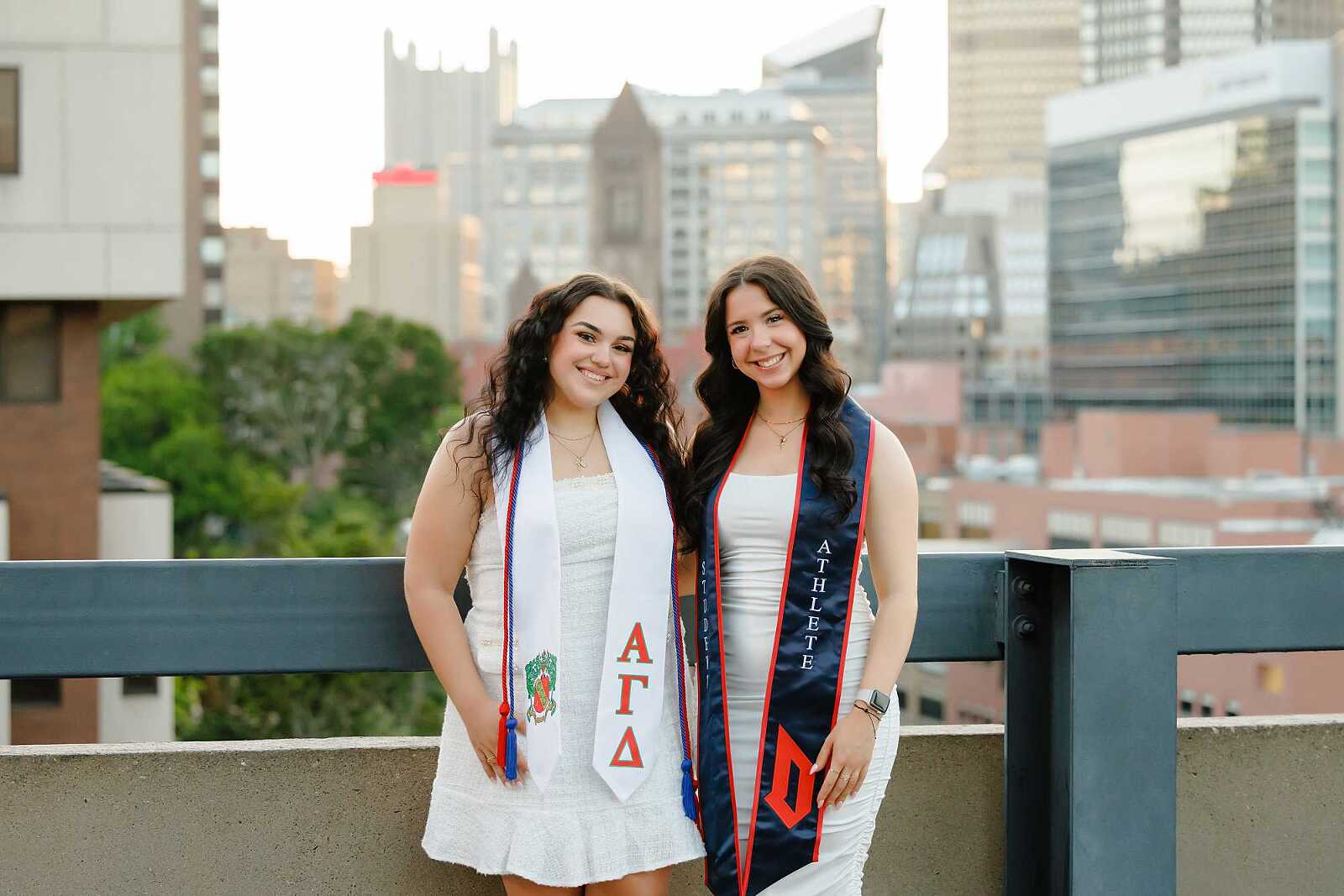 College graduates standing in front of Pittsburgh skyline at Duquesne University