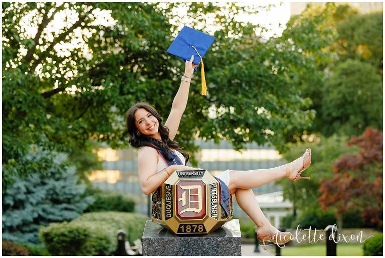 College Graduates Sitting in Ring and Holding up Hat on Duquesne University Campus in Pittsburgh