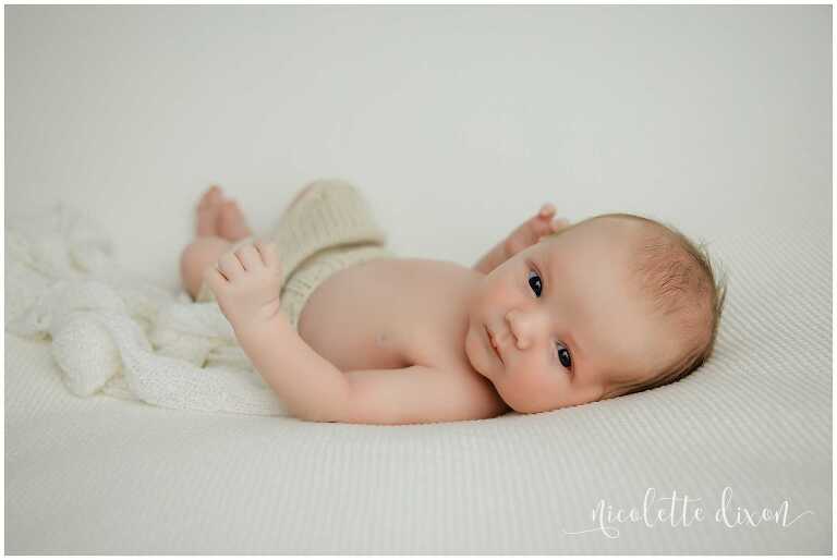 Newborn baby boy laying on white blanket in studio in North Fayette Township near Pittsburgh.